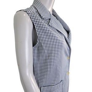 May include: A sleeveless vest with a white and blue houndstooth pattern. The vest has a collar and a button closure.