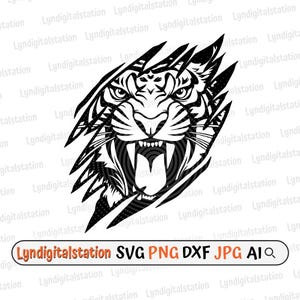 Puede incluir: Ilustración en blanco y negro de la cara de un tigre rugiendo, con dientes afilados y ojos intensos, rompiendo un fondo rasgado. Incluye el texto "Lyndigitalstation SVG PNG DXF JPG AI".