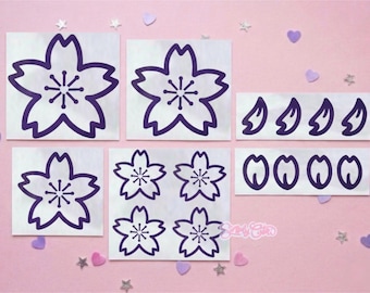 May include: A collection of purple cherry blossom stickers in various shapes and sizes. The stickers include full blossoms, petals, and other floral elements. The stickers are on a white background, with a pink background and decorative accents.