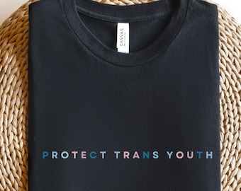 May include: Black t-shirt with the text "PROTECT TRANS YOUTH" in rainbow colors.