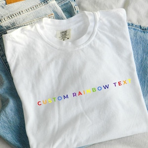 May include: White t-shirt with the text "CUSTOM RAINBOW TEXT" in rainbow colors.