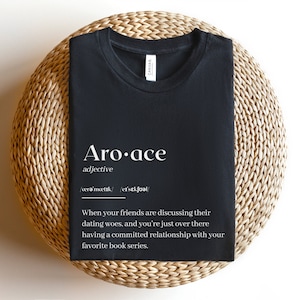 May include: Black t-shirt with white text defining "Aro-ace" as an adjective, meaning "not experiencing romantic or sexual attraction".