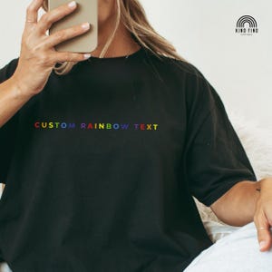 May include: Black oversized t-shirt with the text "CUSTOM RAINBOW TEXT" in rainbow colors.