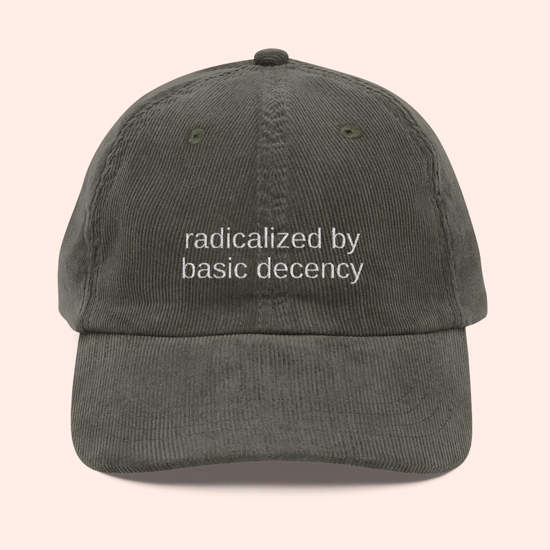 Puede incluir: Gorra de b&eacute;isbol de pana verde oscuro con la frase "radicalized by basic decency" bordada en blanco. La gorra tiene una visera curva y una correa ajustable.
