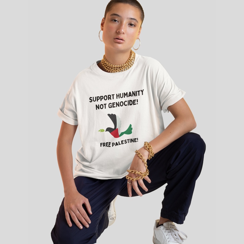 May include: White t-shirt with a black and green dove graphic and the text "SUPPORT HUMANITY NOT GENOCIDE! FREE PALESTINE!"