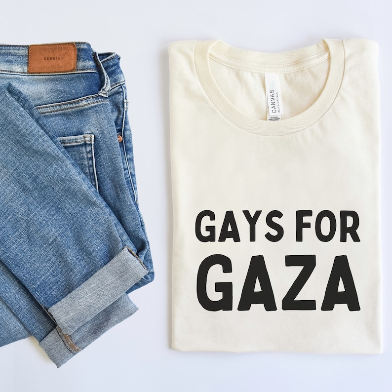 May include: A white t-shirt with the text "GAYS FOR GAZA" printed in black.