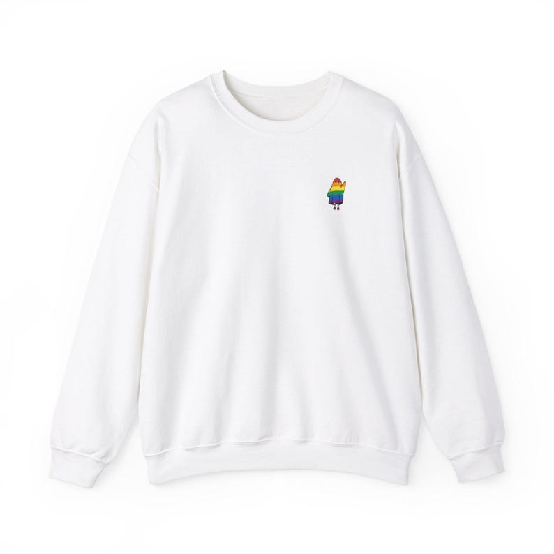 May include: White crew neck sweatshirt featuring a small, embroidered figure on the left chest. The figure is a person with a rainbow-coloured outfit. The sweatshirt has long sleeves and a classic, casual design.
