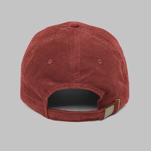 Puede incluir: Gorra de b&eacute;isbol de pana color ladrillo. La gorra presenta una visera curva, un dise&ntilde;o de seis paneles y una correa ajustable con una hebilla color lat&oacute;n. La parte trasera de la gorra tiene una peque&ntilde;a abertura para la ventilaci&oacute;n.