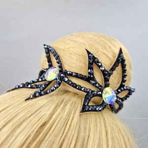 May include: Black hair accessory with crystal embellishments in the shape of two stylised leaves.
