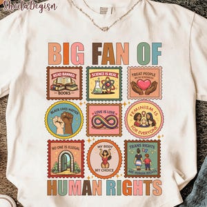 Könnte beinhalten: Weißes T-Shirt mit einem farbenfrohen Grafikdesign. Das Design zeigt den Text "BIG FAN OF HUMAN RIGHTS" und verschiedene stempelförmige Illustrationen mit Botschaften wie "READ BANNED BOOKS" und "TRANS RIGHTS ARE HUMAN RIGHTS".