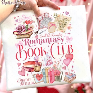 Könnte beinhalten: Weißes Kissen mit einem farbenfrohen Design mit Büchern, Herzen, Blumen und dem Text "Romantasy Book Club" und "Fairytale Retelling". Das Design enthält rosa und rote Akzente.