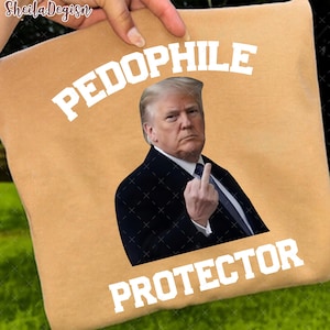 May include: Tan pillow with the words "PEDOPHILE PROTECTOR" in white block letters. A photo of a man in a suit is in the center, giving the middle finger.