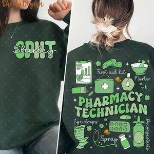 May include: Green sweatshirt with the text "Shirley" on the front and a design of pharmacy-related items on the back, including a mortar and pestle, pills, a first aid kit, and the text "Pharmacy Technician".