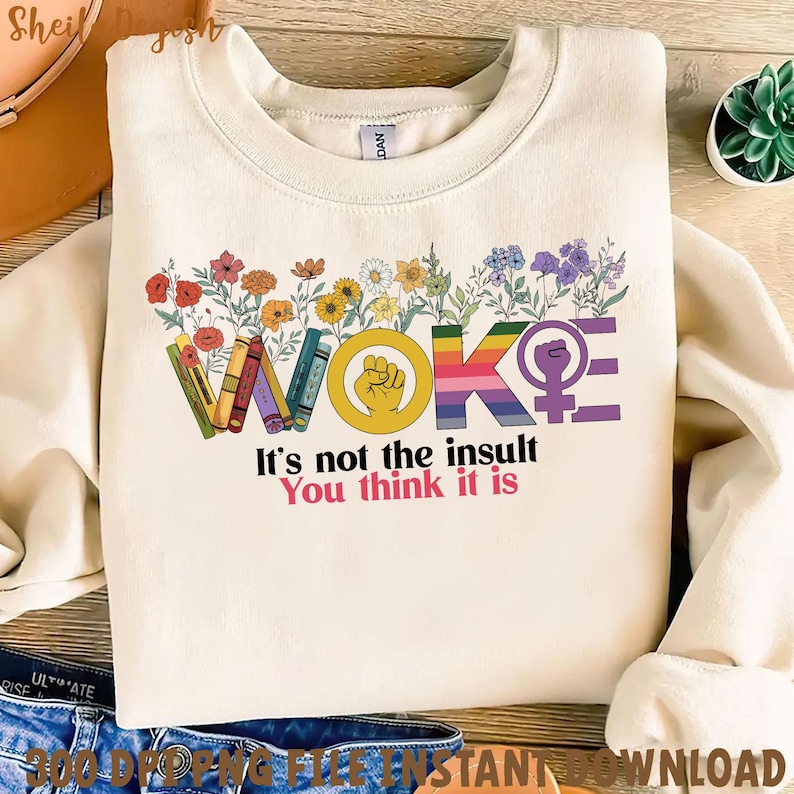 Pu&ograve; includere: Una felpa bianca con un design grafico che dice "WOKE" in lettere arcobaleno con fiori e libri che circondano la parola. Il testo sotto la grafica dice "Non &egrave; l'insulto che pensi".