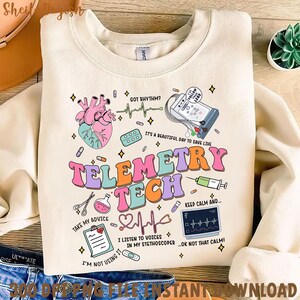 May include: Cream-colored sweatshirt with a colorful design featuring medical-themed illustrations and text. The design includes a heart, EKG, pills, and the words "Telemetry Tech." Additional text includes "Got Rhythm?" and "It's a beautiful day to save lives."