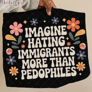 Puede incluir: Camiseta negra con el texto blanco "IMAGINE HATING IMMIGRANTS MORE THAN PEDOPHILES", rodeado de diseños florales y hojas coloridas. La camiseta tiene una estética retro.