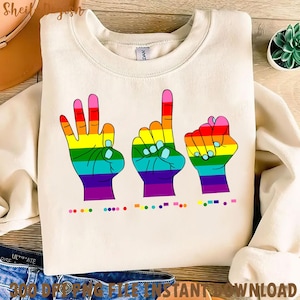 May include: A white sweatshirt featuring a rainbow design of three hands signing the word "love" in American Sign Language. The design includes a row of dots representing braille.