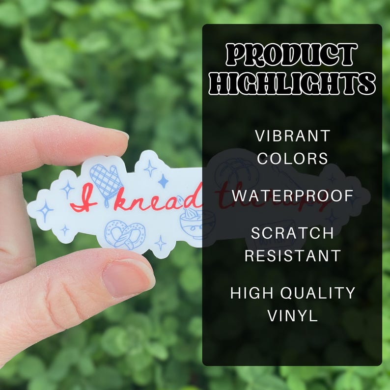 May include: A white sticker with the text "I knead therapy" in red script, with blue illustrations of a mitten, pretzel, and other baking-related items. The sticker is held in a hand against a green background.