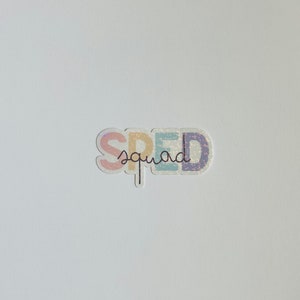 Pu&ograve; includere: Un adesivo bianco con la parola "SPED" in colori arcobaleno e la parola "squad" scritta in corsivo nero sotto.