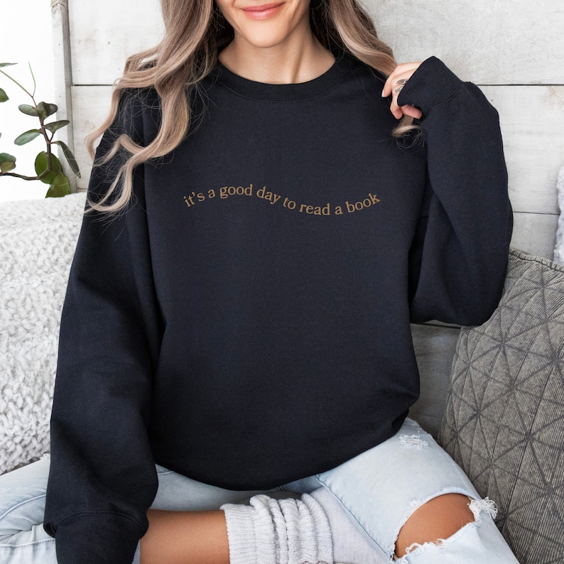 May include: Black sweatshirt with the text "it's a good day to read a book" in brown lettering.