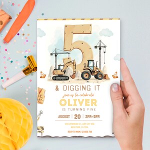 Pu&ograve; includere: Un invito di compleanno a tema costruzioni. Il design presenta un grande numero 5, veicoli da cantiere e il testo "& Digging It". L'invito &egrave; tenuto in mano.