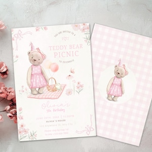 May include: Pink teddy bear picnic party invitation with a pink and white gingham pattern on the back. The invitation features a teddy bear wearing a pink dress and a party hat. The text on the front reads "You are invited to a Teddy Bear Picnic to celebrate Olivia's 1st Birthday".