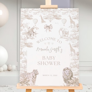 May include: A baby shower sign on an easel, with a safari theme including giraffes, elephants, and a lion. The sign says "Welcome to Amanda Smith's Baby Shower" with the date March 13, XXXX. Balloons are in the background.