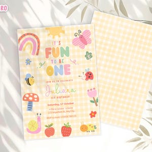 May include: A cheerful invitation for a first birthday celebration. The design features a yellow gingham pattern, a rainbow, sun, butterfly, and other cute illustrations. The text reads "It's Fun to be One" and includes the name "Juliana".
