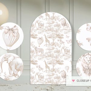 May include: A set of five white and gold round paper cutouts featuring a hot air balloon, an elephant, a lion, a giraffe, and butterflies. The cutouts are decorated with a delicate floral pattern and are perfect for a safari-themed party.