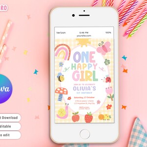 May include: A smartphone displays a colorful birthday invitation with the text "ONE HAPPY GIRL." The design includes a rainbow, butterfly, bee, and other whimsical illustrations. The phone is on a pink surface with party supplies.