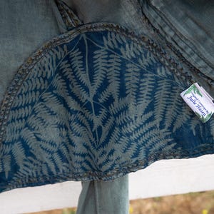 Puede incluir: Una chaqueta vaquera azul con un forro de estampado de helechos y una etiqueta blanca que dice "Designed & Crafted by Julie Hasen".