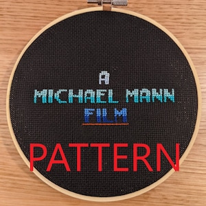 Puede incluir: Un aro de bordado negro con un patrón de punto de cruz que dice "A MICHAEL MANN FILM" en hilo azul y blanco. La palabra "PATTERN" está escrita en rojo debajo del diseño.
