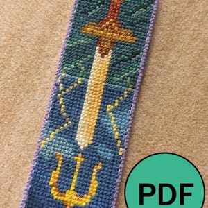 May include: A cross-stitch bookmark with a design of a sword, trident, and clouds in blue, yellow, and red. The bookmark has a purple border and the word "PDF" in a green circle.