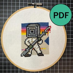 May include: A cross-stitch pattern in a wooden embroidery hoop featuring a pixelated character with a square head holding a long spear. The background shows a sunset gradient of blue, purple, orange, and yellow. A green circle with the text PDF is visible.