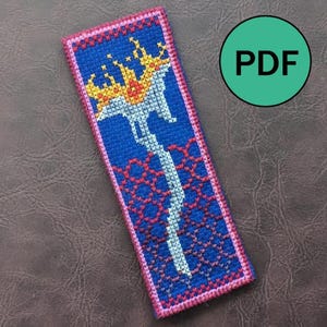 Peut inclure: Marque-page fait à la main avec un fond bleu et un motif central d'une épée blanche avec une flamme dorée et rouge. Le marque-page est bordé de coutures roses et rouges, et le texte "PDF" est dans un cercle vert.