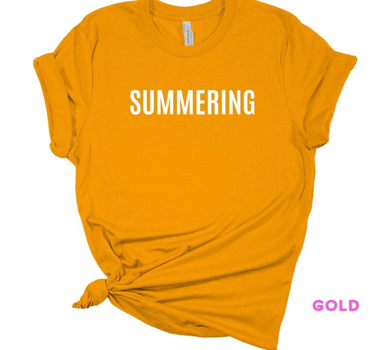 May include: A gold colored t-shirt with the word "SUMMERING" printed in white on the front.