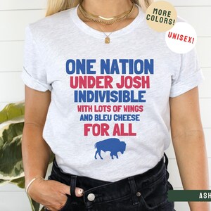 May include: A gray t-shirt with the text "One Nation Under Josh Indivisible with lots of wings and bleu cheese for all" in red, blue, and white. A blue buffalo silhouette is below the text.