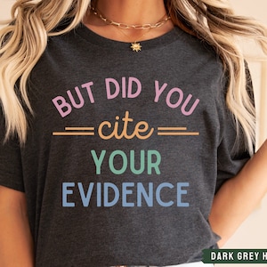 Op de afbeelding: Donkergrijs heather t-shirt met de tekst "But did you cite your evidence" in kleurrijke letters.