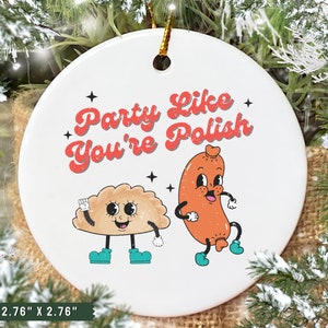 May include: A white ceramic ornament with the text "Party Like You're Polish" in red and white. The ornament features a cartoon pierogi and sausage with smiling faces.