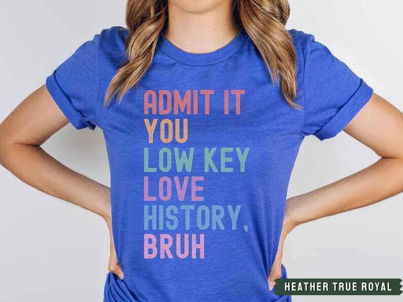 Puede incluir: Una camiseta azul real con el texto "ADMIT IT YOU LOW KEY LOVE HISTORY, BRUH" en colores arco&iacute;ris.