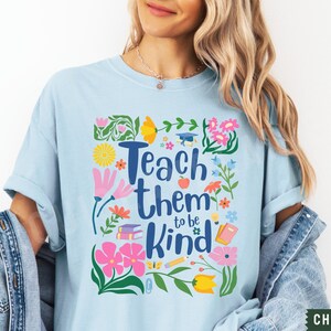 May include: Light blue t-shirt with a floral design and the text "Teach them to be kind".