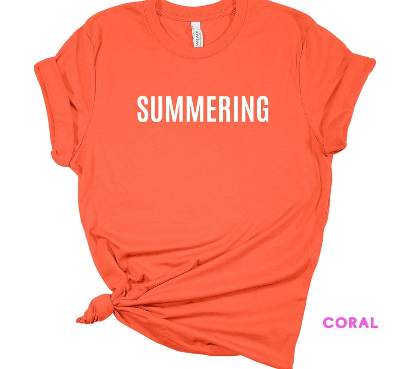 May include: Coral colored t-shirt with the word "SUMMERING" printed in white on the front.