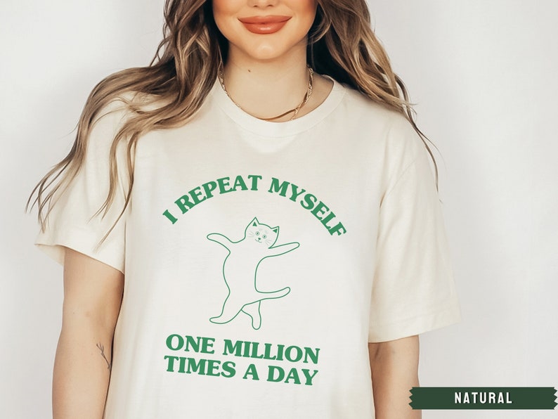 May include: A white t-shirt with a green graphic of a cat dancing and the text "I repeat myself one million times a day".