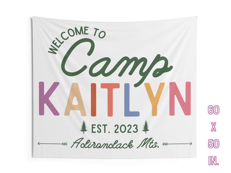 May include: A white tapestry with green text that reads "Welcome to Camp Kaitlyn" in a colorful rainbow font. The text "EST. 2023" and "Adirondack Mts." are also included in green text. The tapestry measures 60 inches by 50 inches.