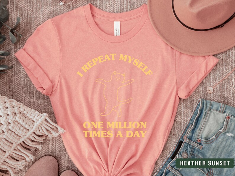 May include: A pink t-shirt with a yellow graphic of a cat and the text "I repeat myself one million times a day".