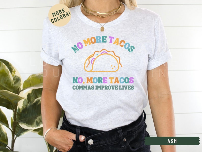 May include: A white t-shirt with the text "NO MORE TACOS NO, MORE TACOS COMMAS IMPROVE LIVES" in colourful letters. The shirt features a graphic of a taco in the centre.