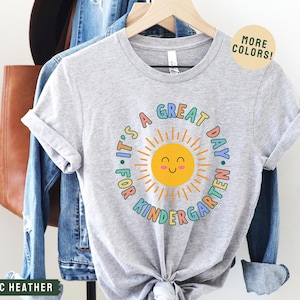 May include: Gray t-shirt with a colorful sun graphic and the text "It's a Great Day. For Kindergarten."