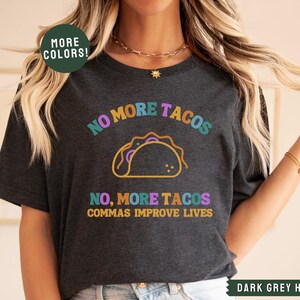 May include: Dark grey heather t-shirt with a colourful graphic of a taco and the text "NO MORE TACOS NO, MORE TACOS COMMAS IMPROVE LIVES".