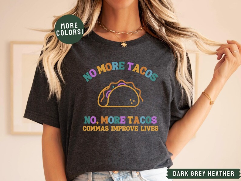 May include: Dark grey heather t-shirt with a colourful graphic of a taco and the text "NO MORE TACOS NO, MORE TACOS COMMAS IMPROVE LIVES".