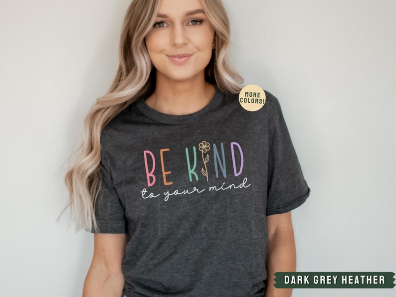 May include: A dark grey heather t-shirt with the text "BE KIND to your mind" in rainbow colors with a small flower graphic.